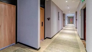 Un pasillo de hotel con puertas de madera, paredes grises y una alfombra estampada.
