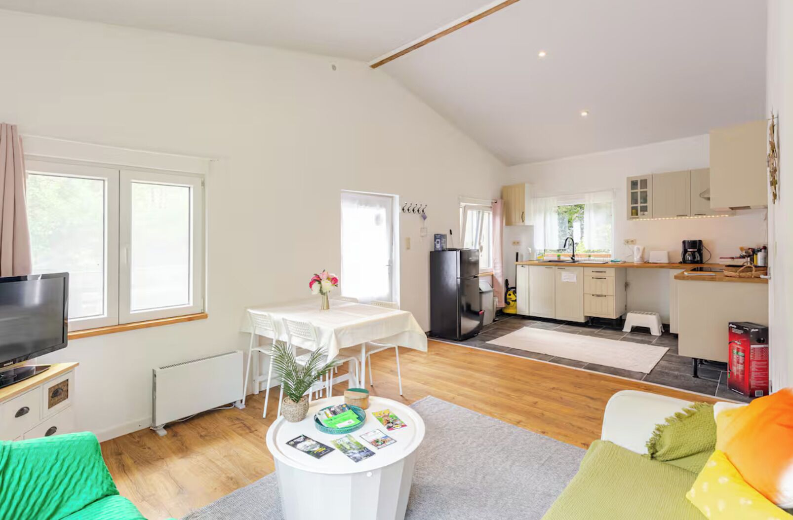 Un espacio habitable amplio con una mesa de comedor, un televisor y una cocina al fondo.