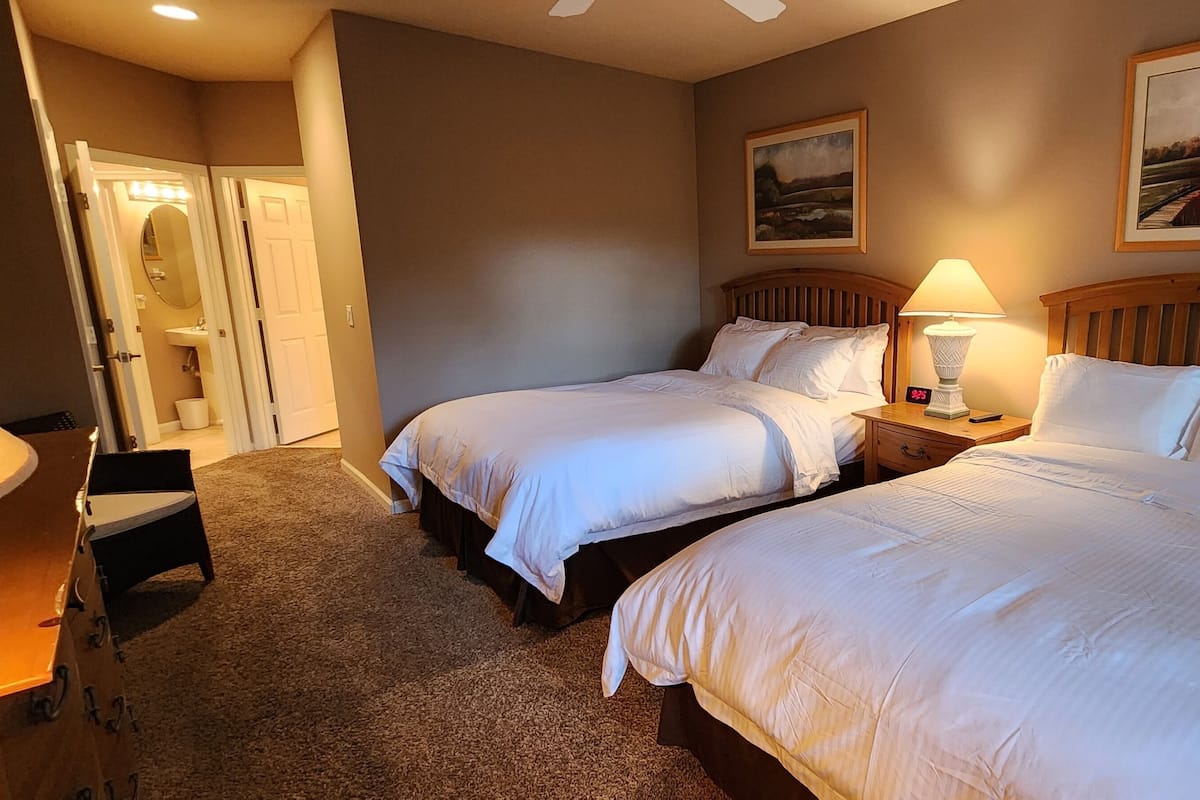 A hotel room with two beds, a desk, and a vanity.