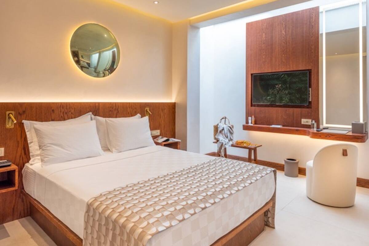 A modern hotel room with a large bed, a TV mounted on the wall, and a small table with a chair.