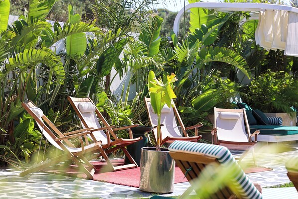 A poolside area with lounge chairs, a potted plant, and a pool.