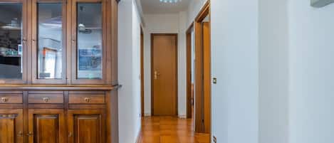 Een gang met een houten kast, een deur en een plafondlamp.