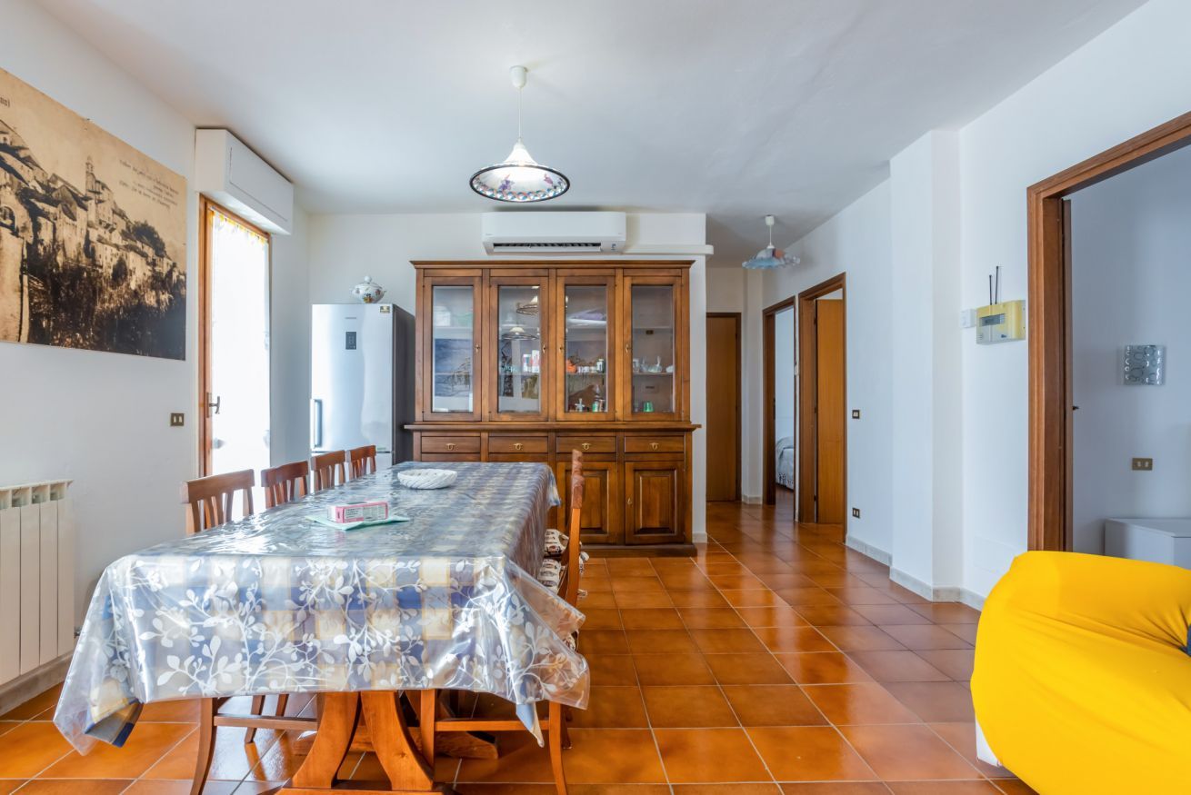 Un comedor con una mesa, sillas, un armario y un sillón de peluche amarillo.
