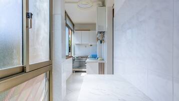 A modern kitchen with white cabinets, a stainless steel oven, and a marble countertop.