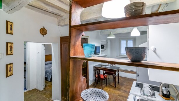 Een keuken met een houten plank, een spoelbak en een eethoek met tafel en stoelen.
