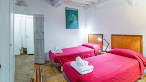 Een kamer met twee bedden, een houten deur, een schilderij en een houten plafond.
