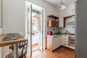A compact kitchen with a dining area, a sliding glass door leading to an outdoor space, and a small table with chairs.