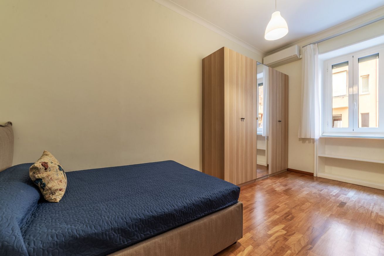 A bedroom with a bed, a wardrobe, and a window.