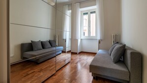 Een moderne kamer met een bank, een spiegel en een raam.
