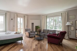 Una habitación con una cama, dos sillones, un sofá, una mesita de centro y una lámpara.