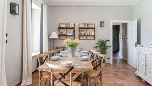 Un coin repas avec une table en bois dressée pour quatre personnes, entourée de chaises, et un vase de fleurs posé sur la table.
