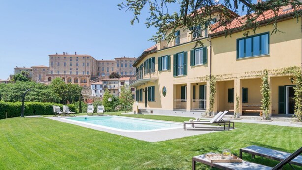 Une piscine avec des chaises longues, une pelouse bien entretenue et un bâtiment doté de balcons.