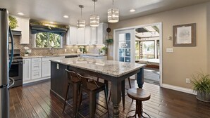 A spacious kitchen with a large island, white cabinets, and pendant lighting. - Indoor Pool & Hot Tub on Golf Course (Loveland)