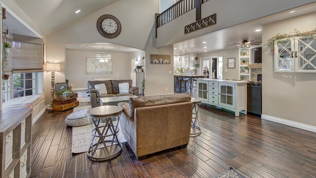 A spacious living room with a high ceiling, a staircase, and a kitchen area. - Indoor Pool & Hot Tub on Golf Course (Loveland)