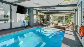 A modern indoor pool area with a clear blue pool, seating area, and a view of the outdoors. - Indoor Pool & Hot Tub on Golf Course (Loveland)