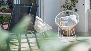 A patio area with two wicker chairs, one with a fluffy pillow and a bottle of alcohol, and another empty. - Lovely home in Visnjan (Visnjan)