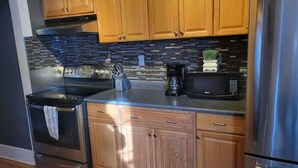 Una cocina moderna con armarios de madera, un refrigerador de acero inoxidable, un microondas, una estufa y una cafetera.