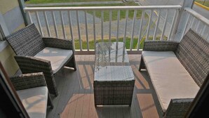 Ein Balkon mit Korbmöbeln und einem Tisch mit Glasplatte.