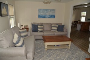 A living room with a sofa, a coffee table, and a painting on the wall.