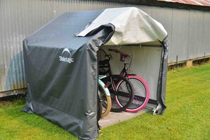 A covered bicycle storage area with a tent, a bicycle, and a pink wheel.