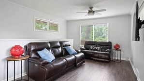 A living room with a brown leather sofa, two side chairs, a ceiling fan, and a window with blinds. - Let the Good Times Roll/ Spacious Retreat 4BE 3BA (Atlanta)