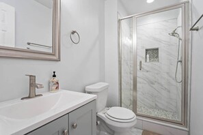 Un baño moderno con ducha acristalada, lavabo blanco y retrete.