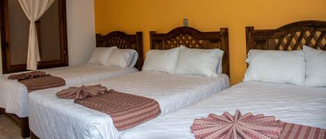 Habitación de hotel con dos camas, cabeceros de madera y una pared amarilla.