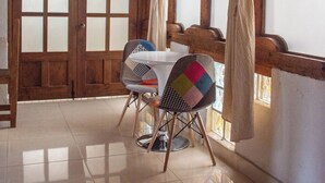 A room with a wooden ceiling, a wooden door with frosted glass panels, a small table with a chair, and a window with curtains. - Hotel Real del Carmen (San Cristóbal de las Casas)