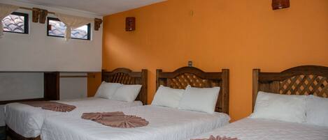 Habitación de hotel con dos camas, cabeceros de madera y una pared de color naranja brillante.