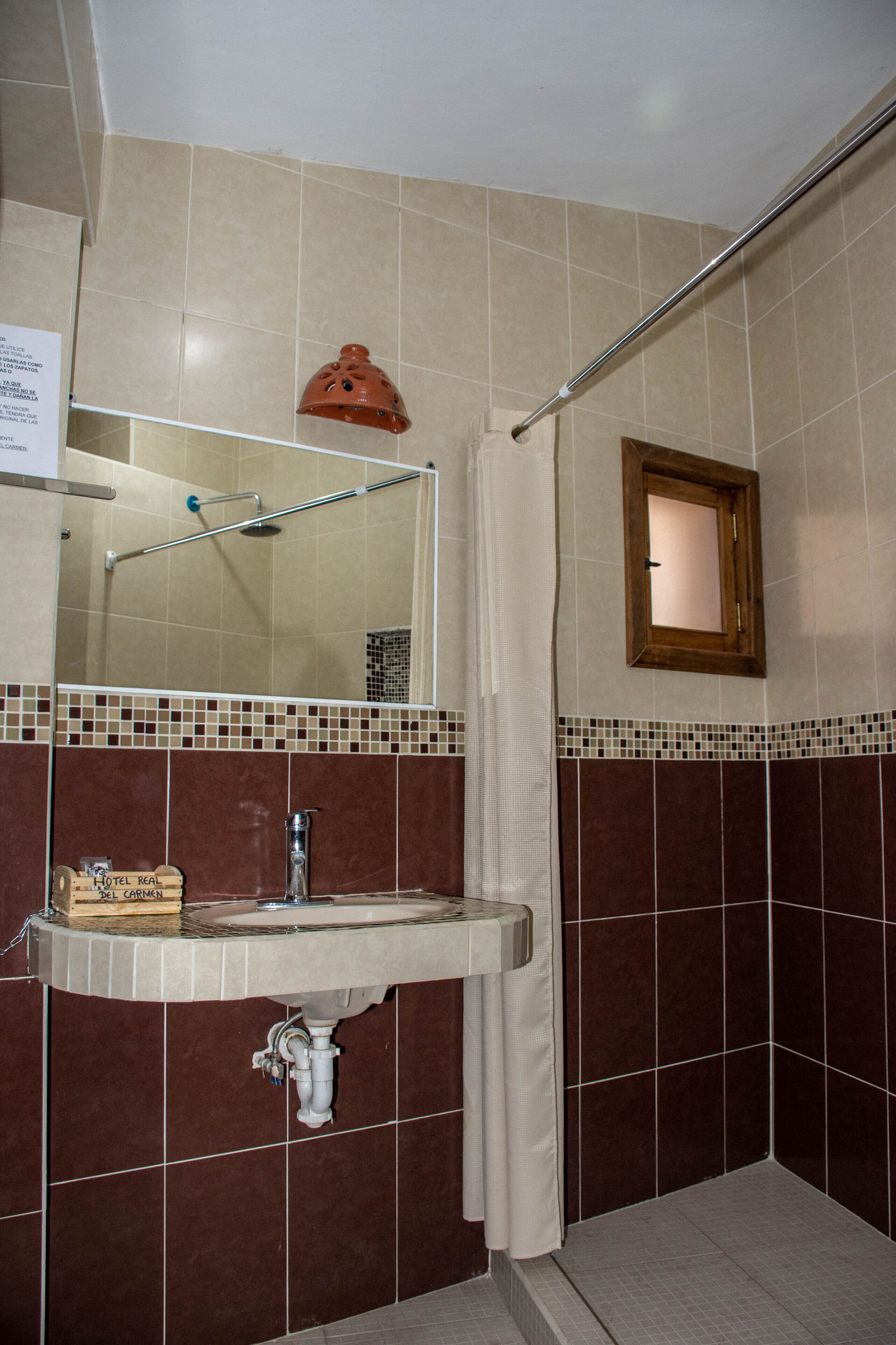 A bathroom with a sink, mirror, shower, and a towel rack.