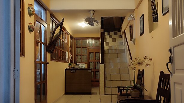 A hallway with a reception desk, a staircase, and a dining area with chairs and a table. - Hotel Posada de la Jungla (Flores)