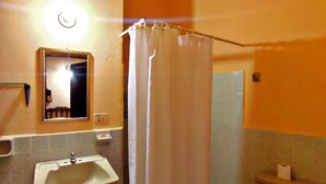 A bathroom with a sink, toilet, and shower curtain. - Hotel Posada de la Jungla (Flores)