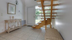 A staircase with a wooden handrail and a landing area with a console table and decorative items. - Hossegor Proche Lac, Villa 8 Personnes, Piscine (HOSSEGOR)