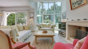 A spacious living room with a large window, a fireplace, and a television. - Hossegor Proche Lac, Villa 8 Personnes, Piscine (HOSSEGOR)