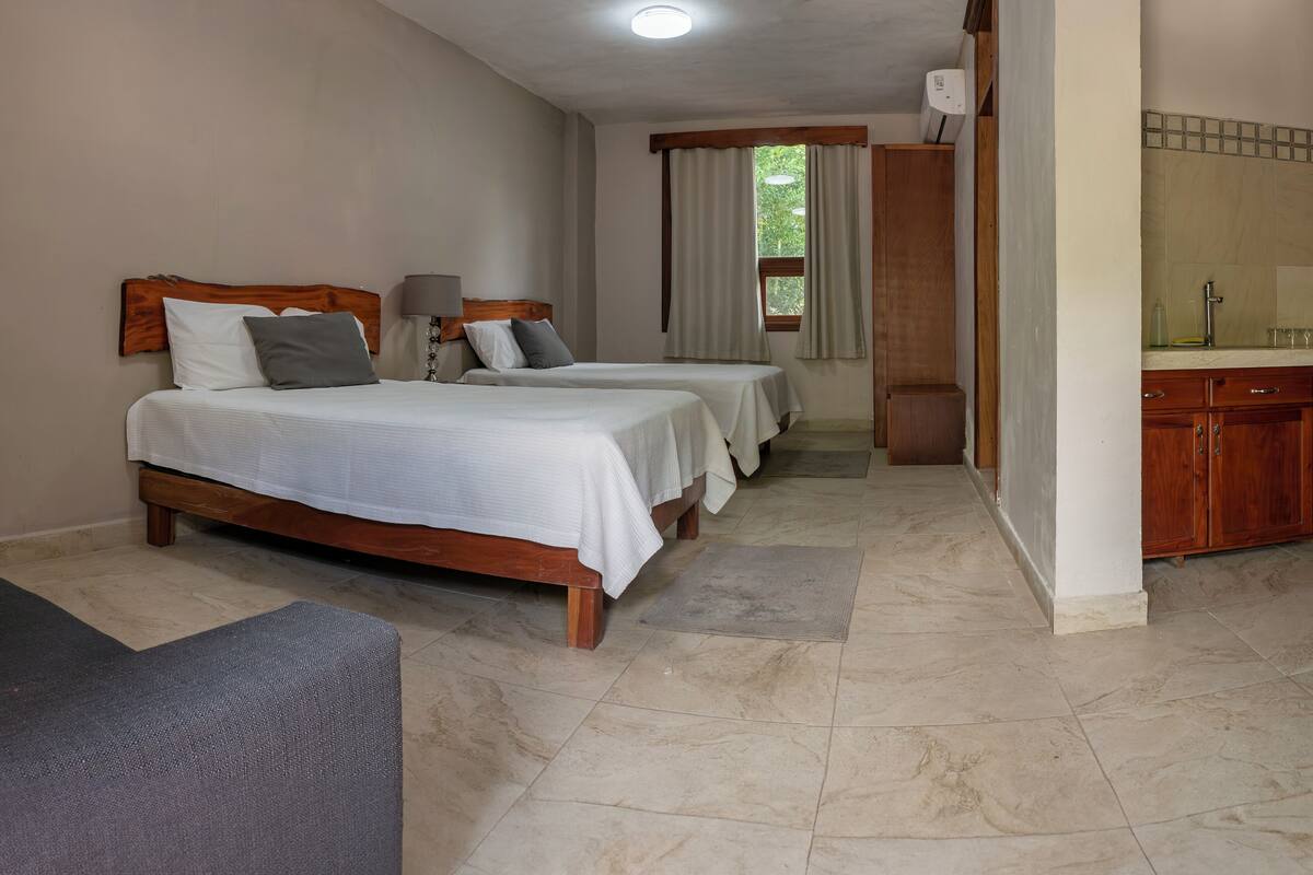 Une chambre d’hôtel avec deux lits, une petite kitchenette et une salle de bain.