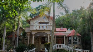 Un bâtiment en pierre de deux étages, avec un toit rouge, un balcon et un escalier menant à l’entrée.