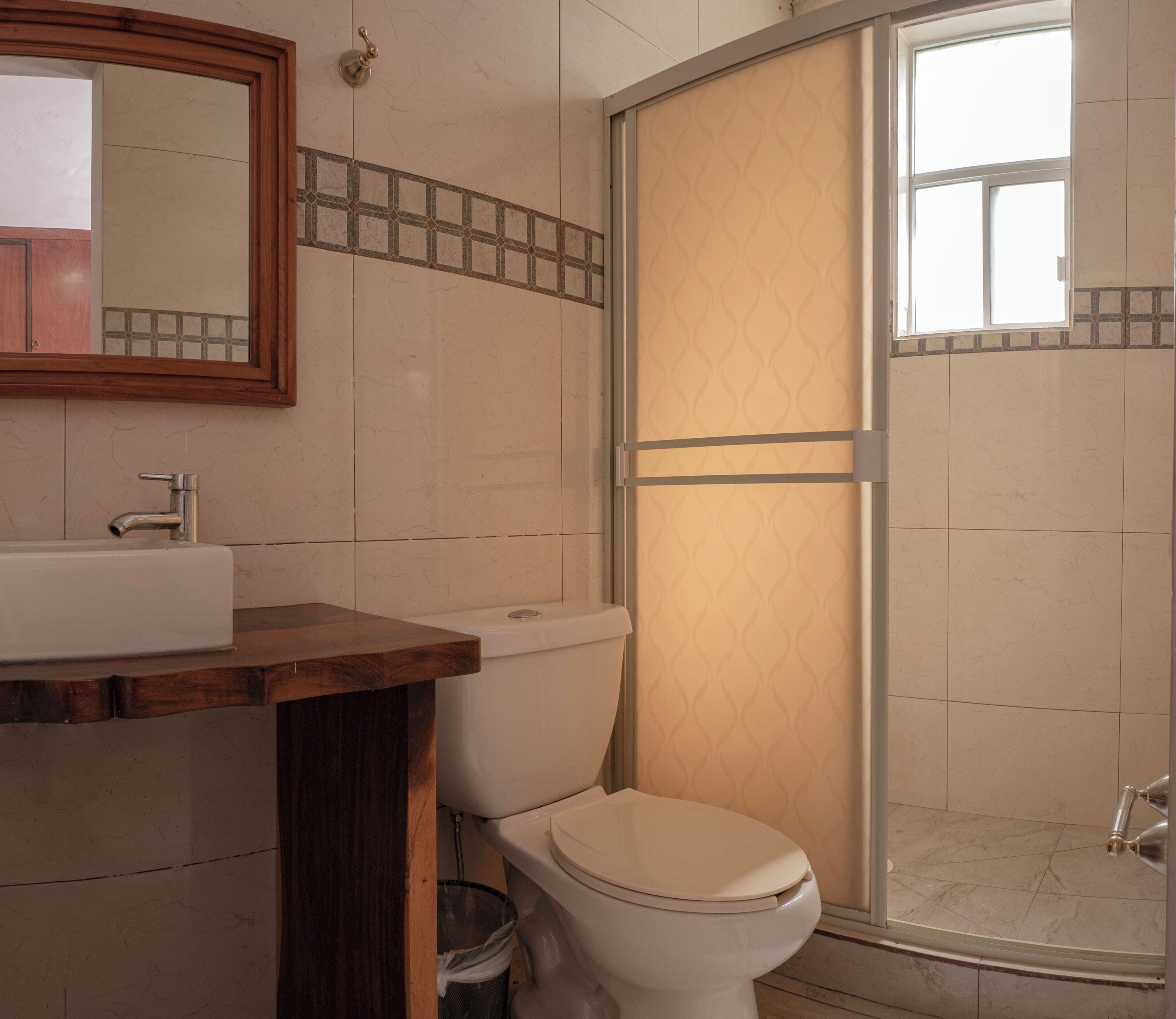 A bathroom with a wooden vanity, a toilet, and a shower enclosure.