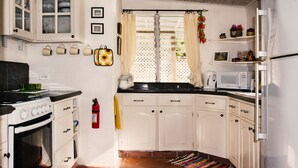 A kitchen with white cabinets, a stove, a microwave, and a refrigerator. - Cosy cottage near the beautiful West Coast beaches (Holetown)