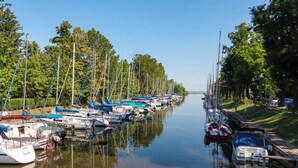 A marina with boats docked along a calm waterway, surrounded by trees and a grassy area. - Holiday home in a quiet location, but close to the center and the beach (Balatonmáriafürdő)