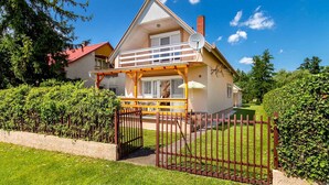 A two-story house with a balcony, a satellite dish, and a gated entrance. - Holiday home in a quiet location, but close to the center and the beach (Balatonmáriafürdő)