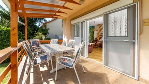 An outdoor patio with a wooden pergola, a table with chairs, and a sliding glass door leading to an interior space. - Holiday home in a quiet location, but close to the center and the beach (Balatonmáriafürdő)