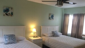 A hotel room with two beds, a nightstand with a lamp, and a ceiling fan. - 19988 Front Beach Rd (Panama City Beach)