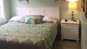 A bedroom with a bed, nightstand, ceiling fan, and artwork on the walls. - 19988 Front Beach Rd (Panama City Beach)