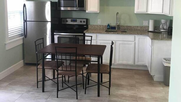 A compact kitchen with white cabinets, a stainless steel refrigerator, a microwave, and a gas stove. - 19988 Front Beach Rd (Panama City Beach)