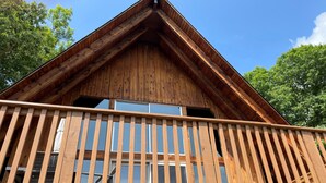 Une cabane en bois dotée d’un balcon et de grandes fenêtres.
