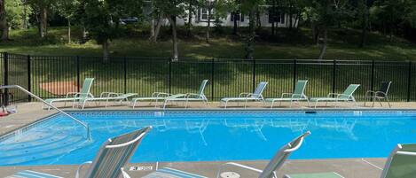 A swimming pool with lounge chairs and a fence.