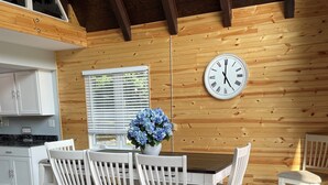 Un coin repas avec un plafond en bois, une horloge et un vase de fleurs.