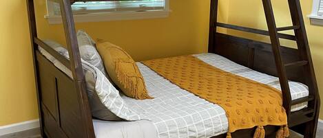 A bunk bed with a wooden frame, white bedding, and a mustard-colored throw blanket.