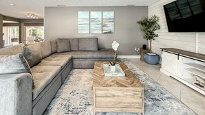 A modern living room with a sectional sofa, a coffee table, and a large TV. - Relaxing Vacation Home on Water Next To Siesta Key (Sarasota)