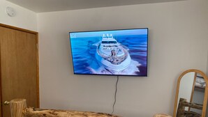 A television mounted on a wall displaying a cruise ship. - Village and Lake Escape - Hot Tub, Walk to Lake & Village, Barbecue (Big Bear Lake)